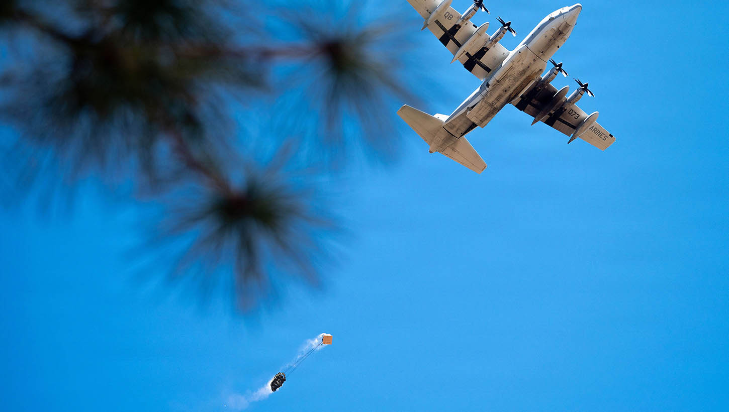 A U.S. Marine Corps KC-130J Hercules conducts a low-level pass over a drop zone