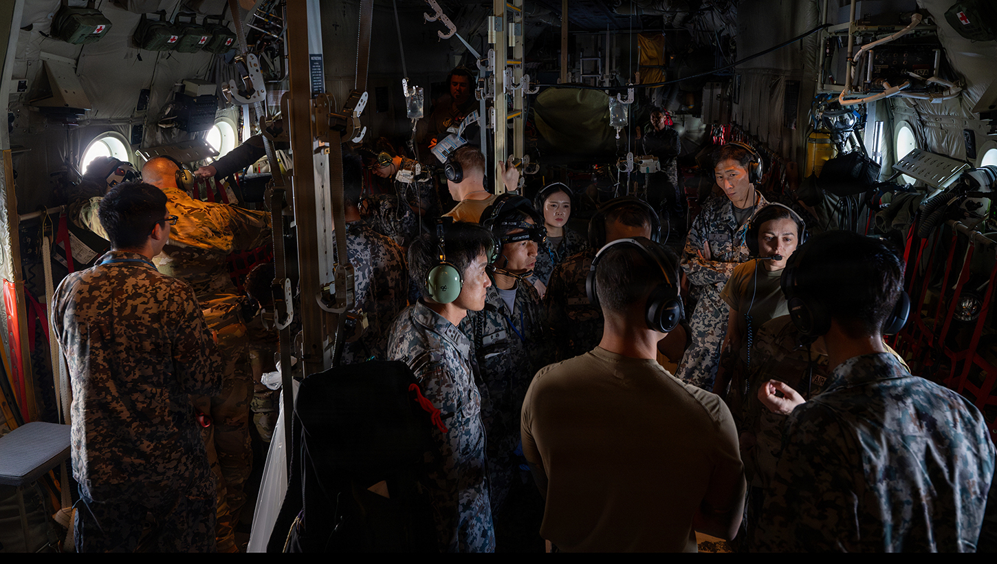U.S. Air Force 18th Aeromedical Evacuation Squadron members and Japan Air Self-Defense Force AES members discuss bilateral training in a KC-130J Hercules assigned to Marine Aerial Refueler Transport Squadron 152 during bilateral training