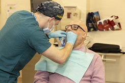 A U.S. Navy physician fits a new dental prosthetic for a patient. DOW photo by Ann Brandstadter.