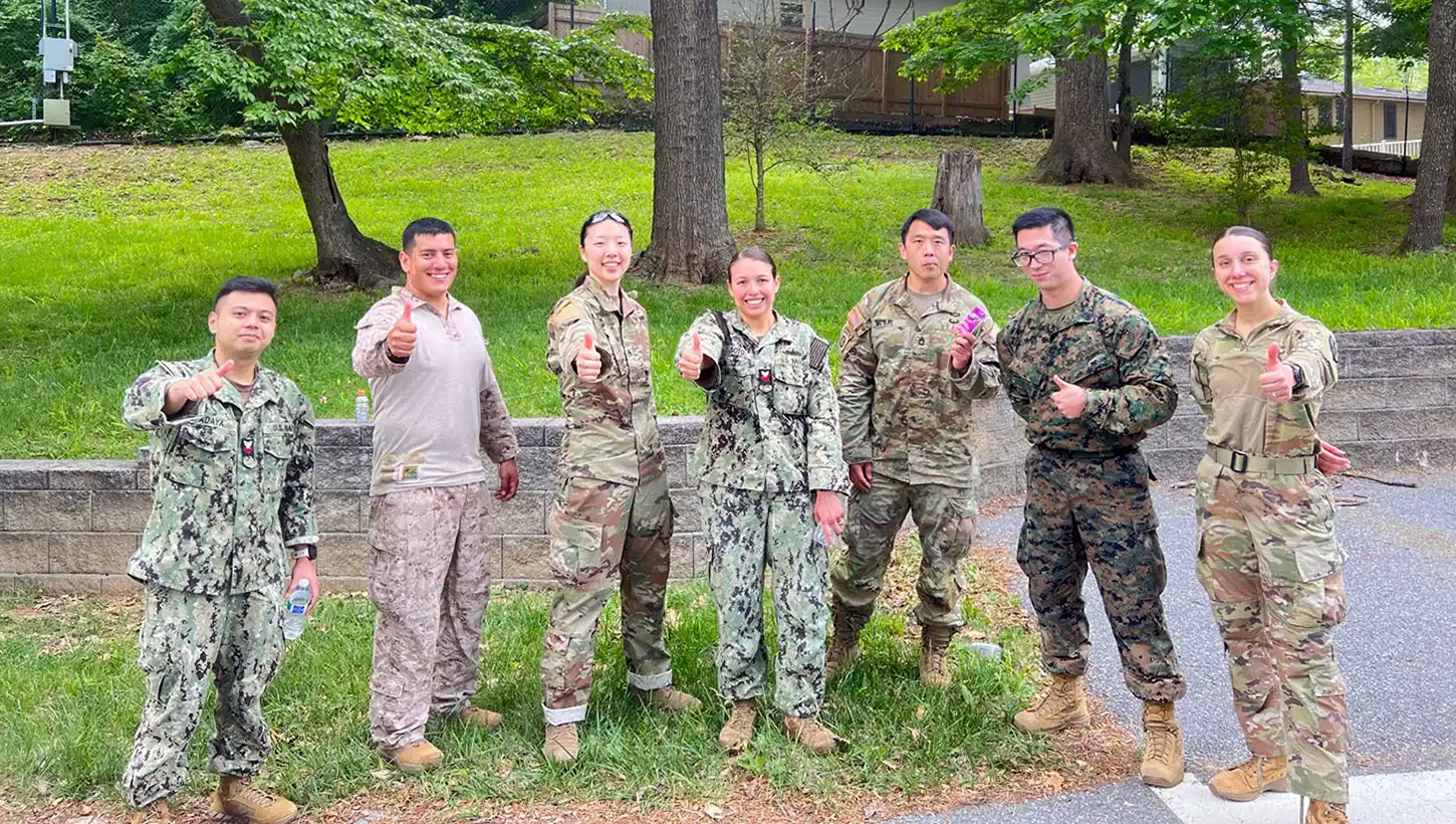 U.S. service members assigned to the Enlisted to Medical Degree Preparatory Program give thumbs-up gestures