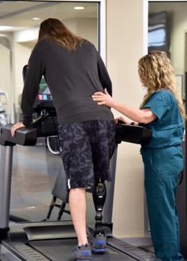 A physical therapist assists a patient on the treadmill.