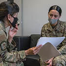 Two military women looking at documents and discussing