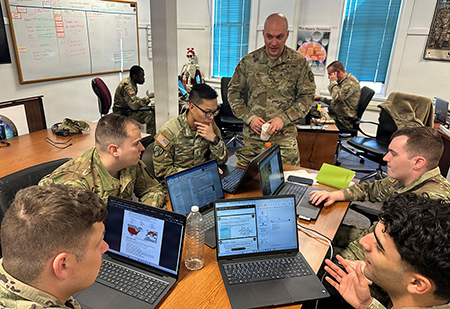 A classroom with service members using laptops and an instructor standing up