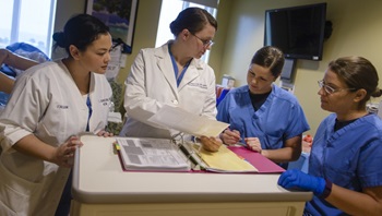 From left, Lt. Christine Johnson, Lt. Cmdr. Rozalyn Love, Lt. Suzanne Papadakos, and Lt. Jessica Dalrymple, review procedures following postpartum hemorrhage training at U.S. Naval Hospital Guam. The training is meant to prepare physicians, nurses, and Corpsmen for postpartum hemorrhage events by teaching how to quantatively measure blood loss. Globally, postpartum hemorraging is the leading cause of death during pregnancy. Quantative measurements create a more accurate portrayal of how serious the bleeding is, which leads to faster and more appropriate treatment. (U.S. Navy photo by USNH Guam Public Affairs/Released)