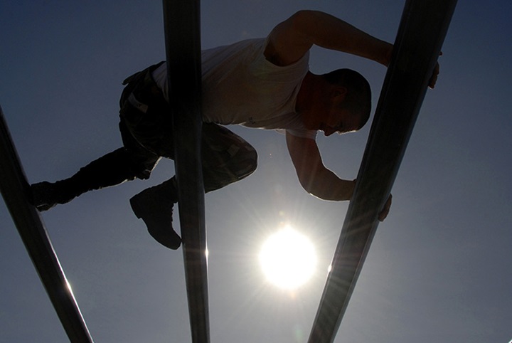 Image of A U.S. Navy Basic Underwater Demolition/SEAL student moves through the weaver during an obstacle course session.