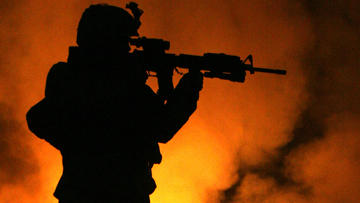 Silhouette of Marine aiming his rifle at a burn pit