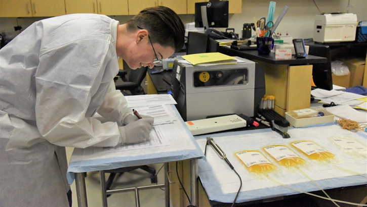 Image of Technician takes notes next to convalescent plasma samples.