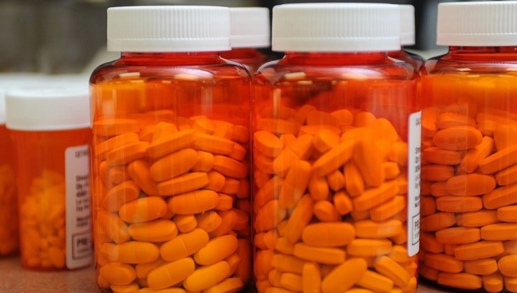 Image of several large prescription bottles filled with pills.