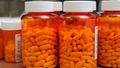 Image of several large prescription bottles filled with pills