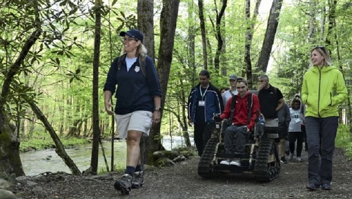 Group of people walking and on wheelchairs through the forest