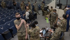 Military personnel wearing face mask standing in line to receive their COVID-19 Vaccine