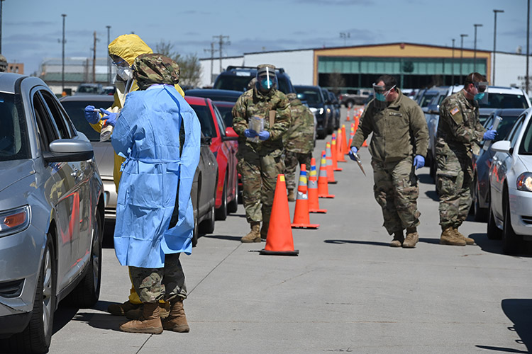 Image of Staff Sgt. Misty Poitra and Senior Airman Chris Cornette, 119th Medical Group, collect throat swabs during voluntary COVID-19 rapid drive-thru testing for members of the community while North Dakota Army National Guard Soldiers gather test-subject data in the parking lot of the FargoDome in Fargo, N.D., May 3, 2020. The guardsmen partnered with the N.D. Department of Health and other civilian agencies in the mass-testing efforts of community volunteers. (U.S. Air National Guard photo by Chief Master Sgt. David H. Lipp).