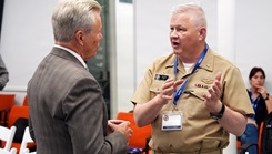 U.S. Navy Capt. Michael Tiller, commanding officer, Naval Medical Research Unit (NAMRU) San Antonio, speaks with John Lamberton of the DLH Corporation at the Defense Health Agency's annual Promote Professional Engagement amongst Military Laboratories (ProPEL) Science Symposium