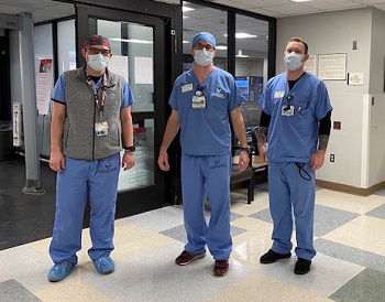 Three men in scrubs wearing masks