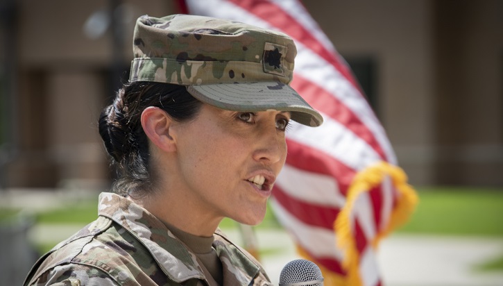 Image of Soldier in front of flag speaking into microphone. Click to open a larger version of the image.