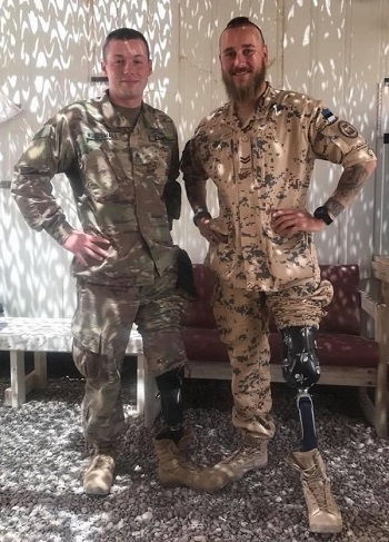 Two soldiers with leg amputations stand next to each other.