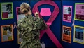 Soldier standing in front of a colorful display with pink ribbon