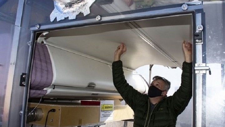 Image of Man wearing mask, looking at ceiling of an airplane.