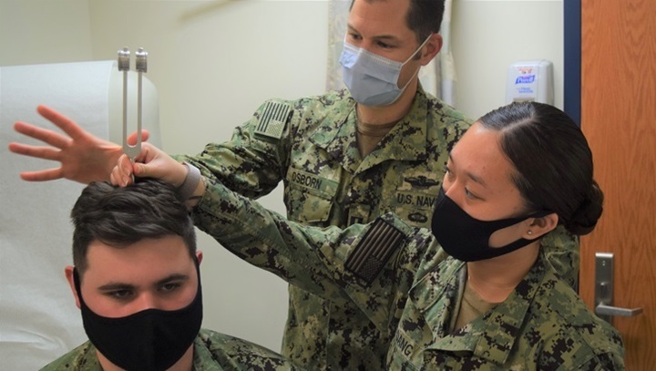 Image of Three soldiers, wearing masks, demonstrating a hearing test.
