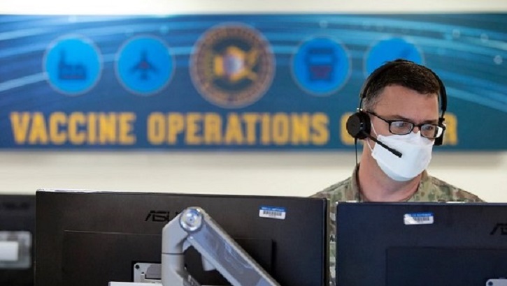 Soldier wearing mask, sitting in front of computer monitors