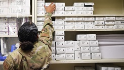 Military personnel in a supply room, reaching for the top shelf