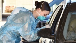 Soldier wearing protective gear leaning into a car to chat with other soldier