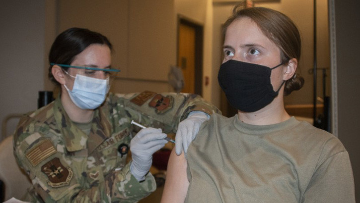 Medical personnel giving a vaccine to a soldier in her right arm