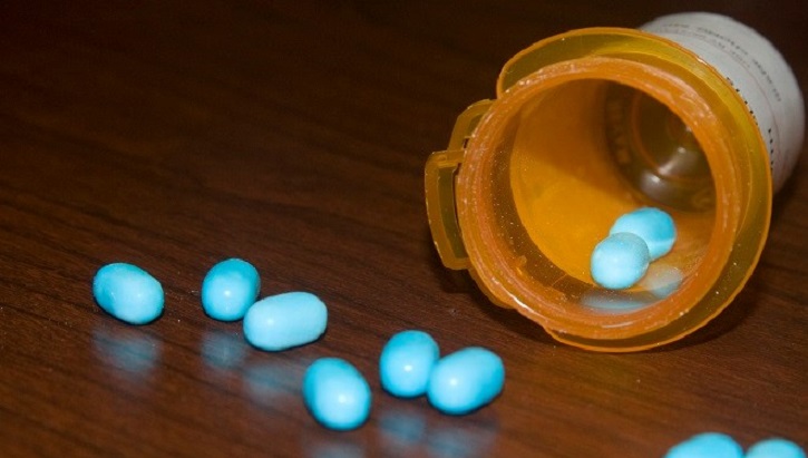 Image of An open bottle of pills, with some spilling out on the table. Click to open a larger version of the image.