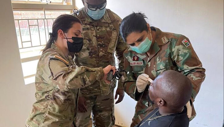 Military medical personnel examine a patient