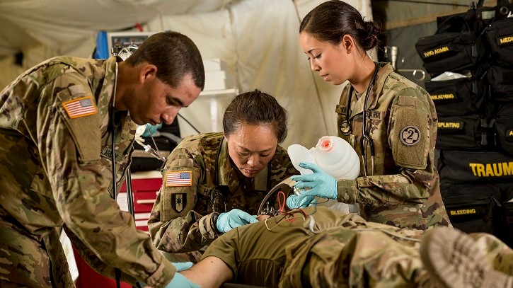 Lt. Col. Juli Fung-Hayes (center), a U.S. Army Reserve emergency medicine physician with the 2nd Medical Brigade, leads a medic team from the 396th Combat Support Hospital, headquartered at Fairchild Air Force Base, Washington, through a trauma and critical care scenario in a field hospital during a promotional photo shoot for Army Reserve marketing and recruiting at Fort Hunter Liggett, California, July 18, 2018. (U.S. Army Reserve photo by Master Sgt. Michel Sauret)