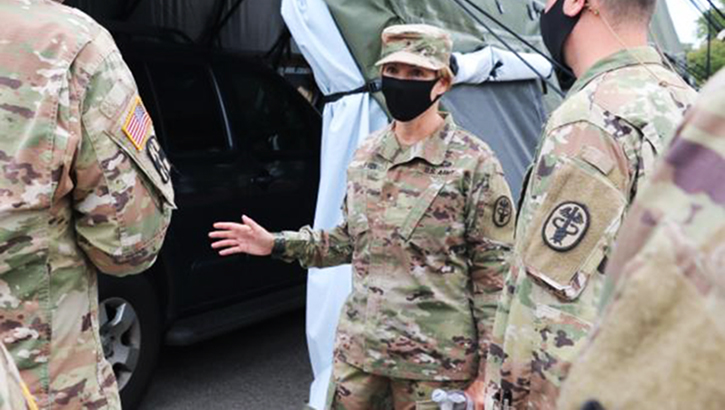 Image of Soldier in mask speaking to other soldiers.