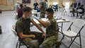 Military medical personnel administering vaccine