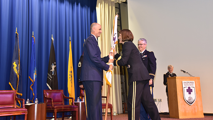 U.S. Air Force Col. Mark Lyman accepts the Walter Reed flag from U.S. Army Brig. Gen. Deydre Teyhen, Director of the National Capital Region Market, during the Joint Pathology Center change of directorship ceremony in Memorial Auditorium.  (Photo: James Black)