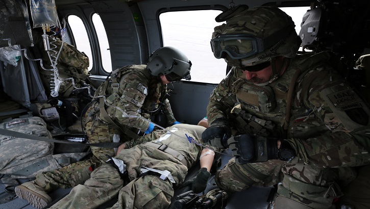 Military nurses working on a simulated patient in a helicopter