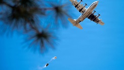 A U.S. Marine Corps KC-130J Hercules conducts a low-level pass over a drop zone
