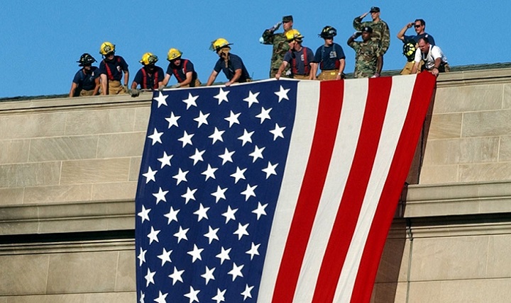 Image of The garrison flag is hung from the still smoldering Pentagon by service members and firefighters. (DoD photo).