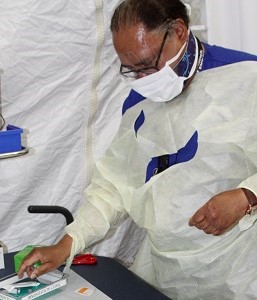 A nurse wearing a mask with needles in a tray