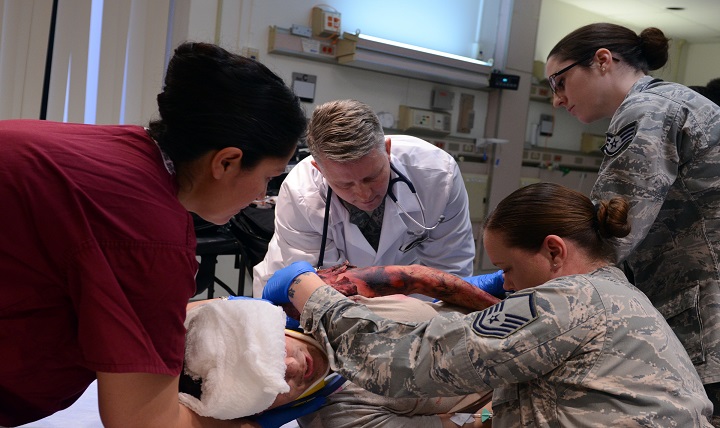 Air Force medical personnel check for puncture wounds on a simulated head wound victim during a training exercise. 