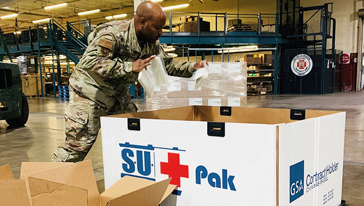 Image of Military member in warehouse, packing a large box. Click to open a larger version of the image.