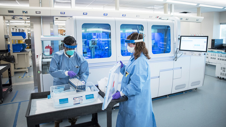 Two technicians in full PPE in a lab