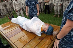 Navy Petty Officer 3rd Class Ryan Adams is being used as an example victim for cooling a heat casualty at the bi-annual hot weather standard operating procedure training aboard Marine Corps Base Camp Lejeune, N.C., Aug. 24. Adams is demonstrating the "burrito" method used to cool a heat related injury victim. Photo by Pfc. Joshua Grant.