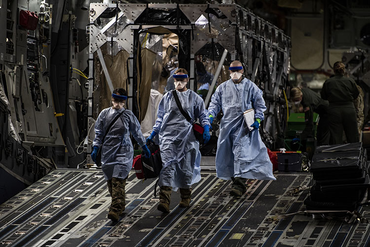 Image of Three U.S. Air Force medical Airmen exit a C-17 Globemaster III aircraft. Click to open a larger version of the image.