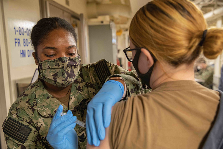 201019-N-PC065-1062 NORFOLK (Oct. 19, 2020) Hospital Corpsman 2nd Class Sashee Robinson, assigned to amphibious transport dock ship USS Arlington (LPD 24), administers an influenza vaccine to Machinery Repairman 2nd Class Hannah Swearingen in medical aboard the Arlington. Influenza vaccines are an annual medical readiness requirement throughout the Department of Defense. (U.S. Navy photo by Mass Communication Specialist 2nd Class John Bellino/Released)