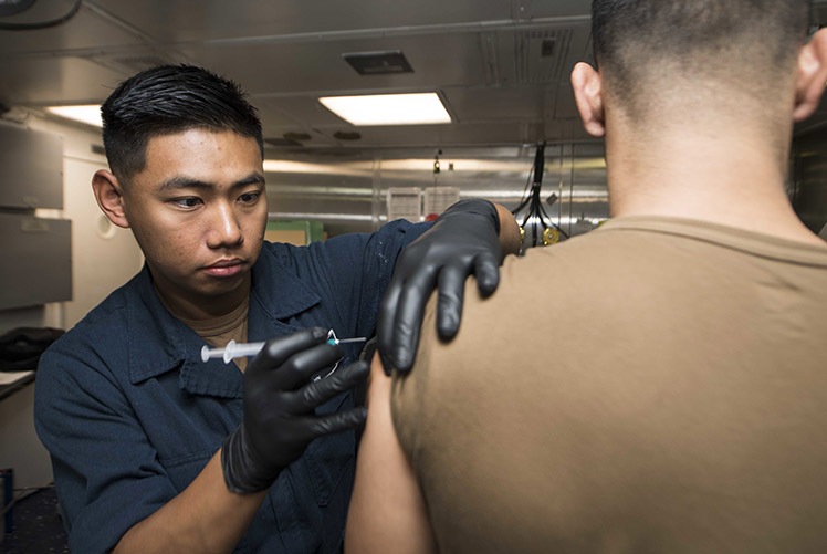 Image of 181129-N-GR847-3000 ARABIAN GULF (Nov. 29, 2018) Hospitalman Jay Meadows, from Weaver, Ala., administers an influenza vaccine to a Sailor during a regularly scheduled deployment of the Essex Amphibious Ready Group (ARG) and 13th Marine Expeditionary Unit (MEU). The Essex ARG/13th MEU is flexible and persistent Navy-Marine Corps team deployed to the U.S. 5th Fleet area of operations in support of naval operations to ensure maritime stability and security in the Central Region, connecting to the Mediterranean and the Pacific through the western Indian Ocean and three strategic choke points. (U.S. Navy photo by Mass Communication Specialist 3rd Class Reymundo A. Villegas III).