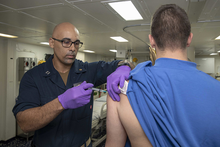 NORFOLK (Oct. 15, 2019) Lt. Sipriano Marte administers an influenza vaccination to Airman Tyler French in the intensive care unit aboard the Wasp-class amphibious assault ship USS Kearsarge (LHD 3). Kearsarge is underway conducting routine training. (U.S. Navy photo by Mass Communication Specialist Petty Officer 3rd Class Jacob Vermeulen/Released)