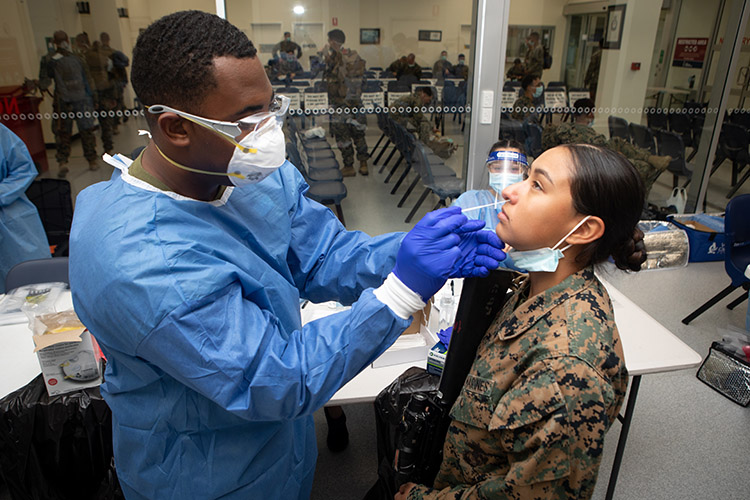 U.S. Navy Hospital Corpsman 2nd Class Julian Gordon, left, a preventative medicine technician with Marine Rotational Force - Darwin, administers a COVID-19 test to a U.S. Marine with MRF-D, at Royal Australian Air Force Base, Darwin, NT, Australia, March 22, 2021. Marines and Sailors with MRF-D are required to conduct strict COVID-19 mitigation procedures prior to arrival in Darwin, in compliance with Northern Territory Health Authorities. All service members must provide three documented negative COVID-19 swab tests throughout their travel and prior to being released from a 14-day quarantine period. (U.S. Marine Corps photo by Sgt. Micha Pierce)