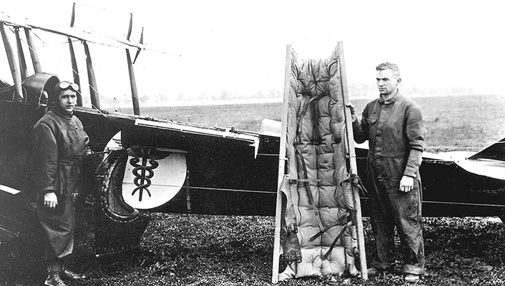Soldier stands next to a Curtiss JN-4 air ambulance.