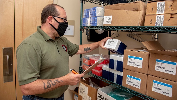 Man wearing mask checking inventory on shelves