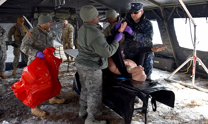 U.S. Navy Lt. Cmdr. Bryan Platt (right), Armed Forces Medical Examiner System forensic pathologist, demonstrates an examination at a simulated Mortuary Affairs Contaminated Remains Mitigation Site during Operation Joint Recovery exercise at Joint Base McGuire-Dix-Lakehurst, N.J., Mar. 10, 2018. Platt familiarized participants in recovery and processing of contaminated remains. (U.S. Air Force photo by Tech. Sgt. Robert M. Trujillo)