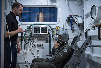 Two men in a training chamber.